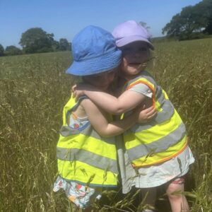 Two young toddler girls embrace in a friendly hug.